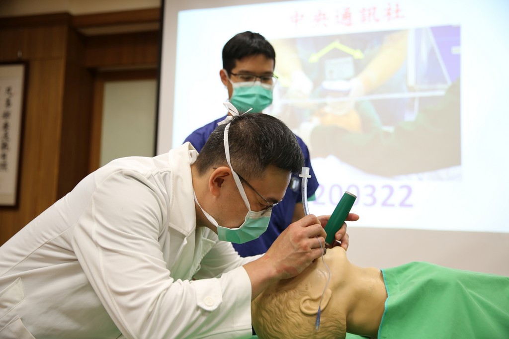 楊曜臨主任(白袍)與黃景旋醫師(藍衣)示範傳統插管(左圖)與利用防疫罩+光視棒插管(右圖)的差別，可以明顯看出新模式有效保護了醫療人員