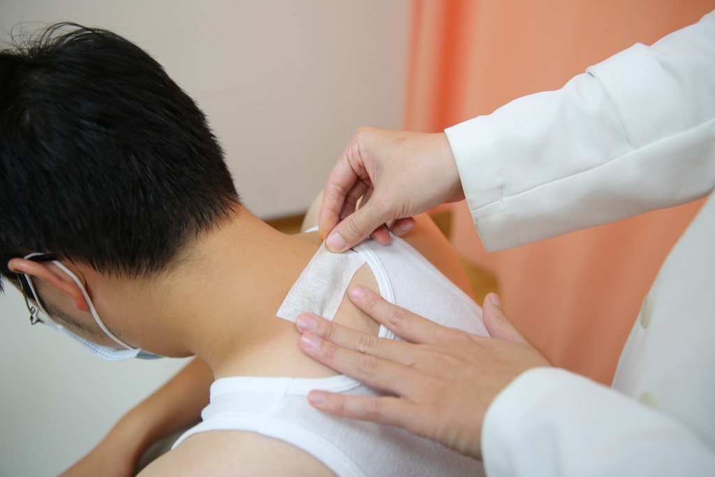 花蓮慈院中醫部陳中奎醫師在病人的大椎穴、定喘穴敷貼三伏貼。