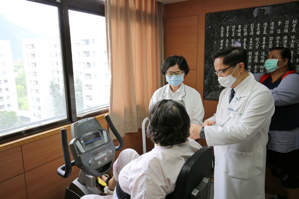 花蓮慈院林欣榮院長(右)為謝女士加油打氣，一旁物理治療師黃意雯(中)指導謝女士使用復健儀器。