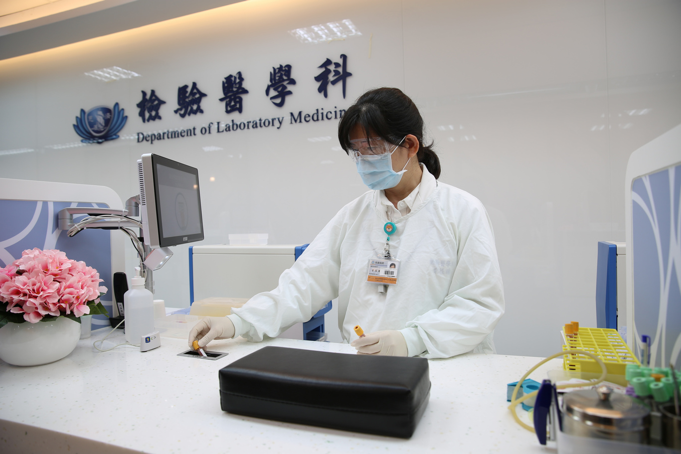 醫檢師採集完病人檢體後，將檢體直接投入桌面上的小窗口，由檢體輸送帶將檢體送入自動化軌道設備。