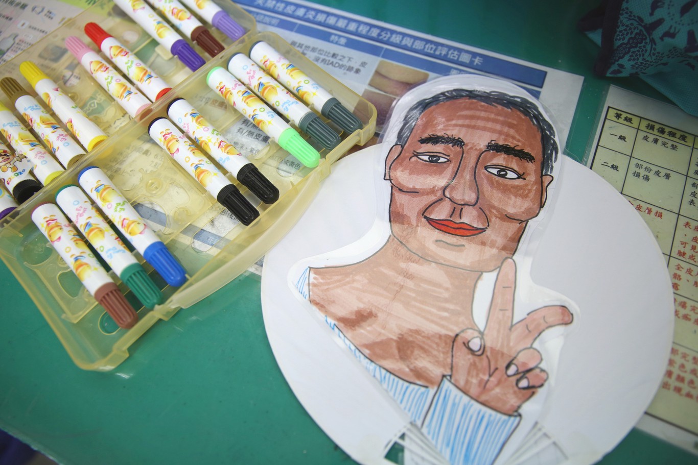 照護陳阿公的輕症病房護理師們繪製有著阿公畫像的Q版扇子,特別畫上阿美族族服代表勇士,祝福阿公平安出院。 照護陳阿公的輕症病房護理師們繪製有著阿公畫像的Q版扇子,特別畫上阿美族族服代表勇士,祝福阿公平安出院。