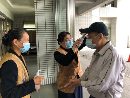 醫療志工在門診大廳協助民眾測量體溫與手部消毒