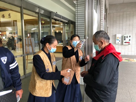 醫療志工在門診大廳協助民眾測量體溫與手部消毒