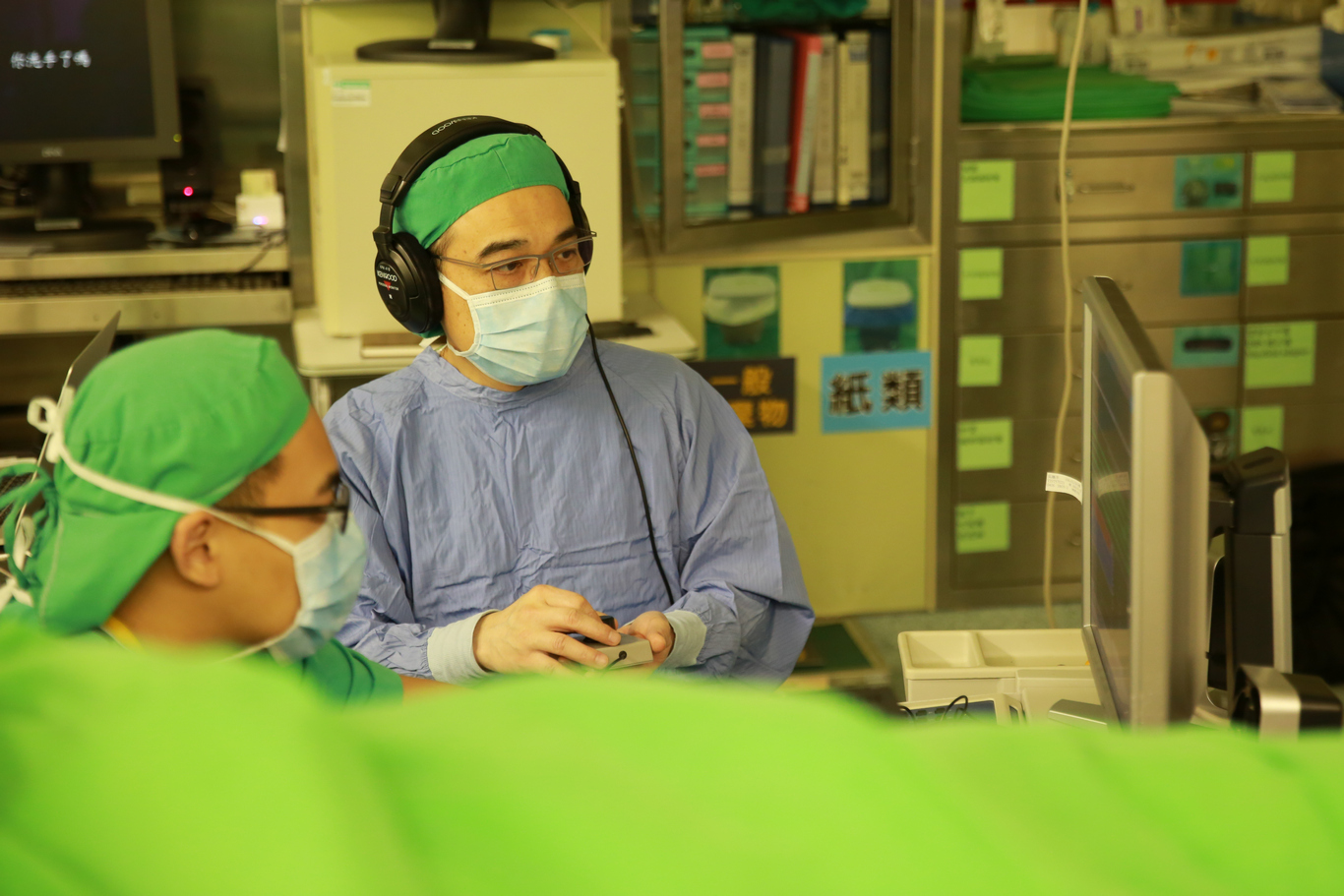 陳新源主任（右）聚精會神地聽著放電訊息，偵測腦神經細胞的微電位訊號，為曉冬調整最適合放置晶片的位置